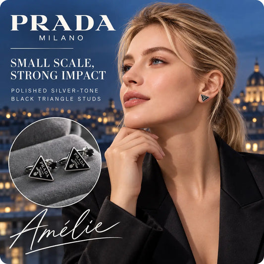 Prada small black triangle stud earrings with silver-tone edges worn by a blonde model at night
